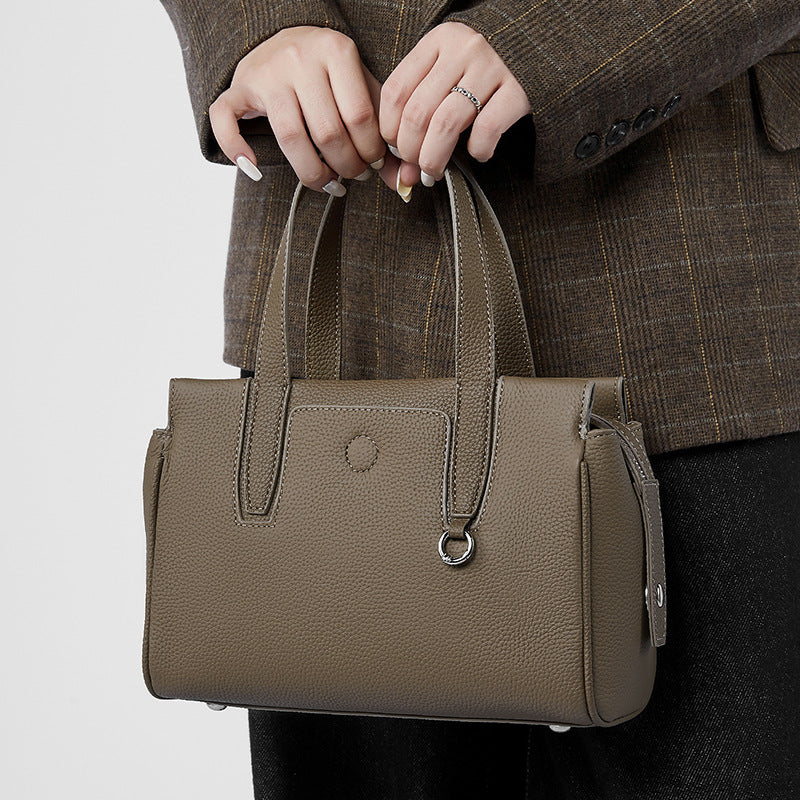 Taupe crossbody bag with top handles, front pocket, and adjustable shoulder strap