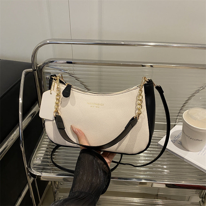 Light cream pebbled shoulder crossbody bag with gold chain handles and black strap