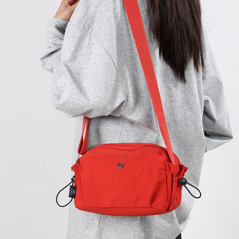 Small red nylon crossbody bag with adjustable strap and zip closure