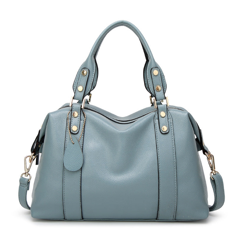 Light blue shoulder bag with dual handles, gold-stud tabs, and side strap tassel pulls
