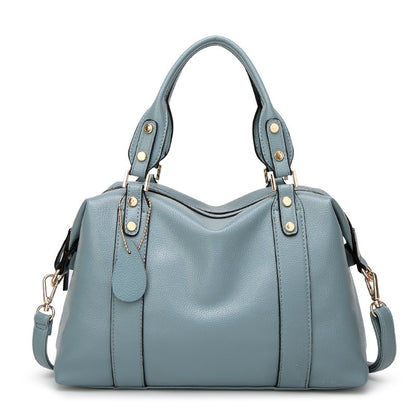 Light blue shoulder bag with dual handles, gold-stud tabs, and side strap tassel pulls