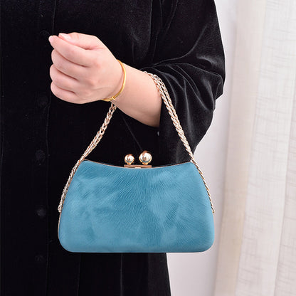 Blue clutch bag with gold-tone chain strap and kiss-lock clasp, carried in hand