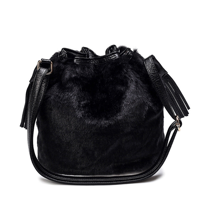 Black faux-fur bucket bag with drawstring top, tassels, and crossbody strap