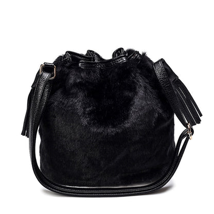 Black faux-fur bucket bag with drawstring top, tassels, and crossbody strap