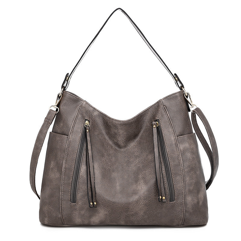 Women's gray shoulder hobo bag with curved top and two front zipper pockets