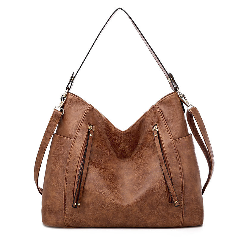 Women's brown shoulder hobo bag with curved top and two front zipper pockets