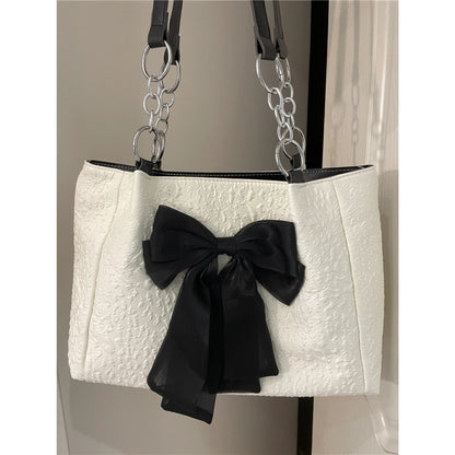 White canvas tote bag with black bow ornament and silver chain handles