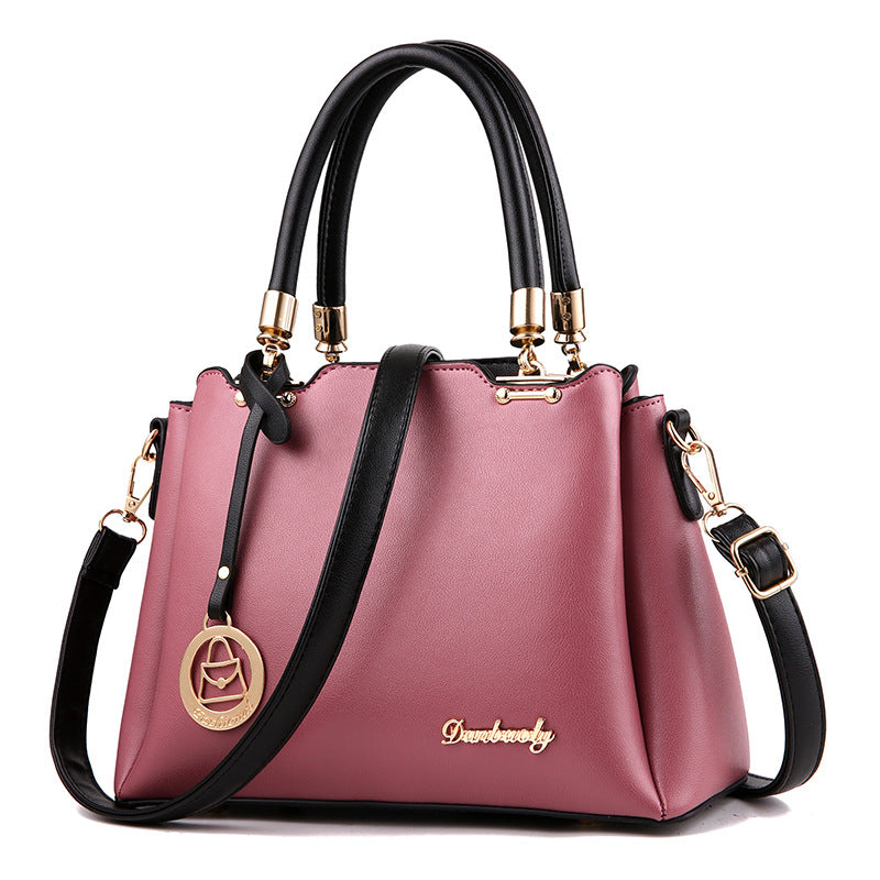 Pink women’s handbag with top handles, gold-tone hardware, and crossbody strap