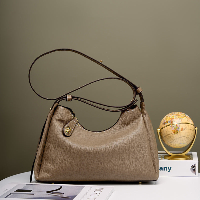 Beige hobo crossbody shoulder bag with curved top handle and gold clasp detail
