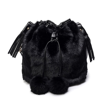 Black faux-fur bucket bag with drawstring top, tassels, and pom-pom trim
