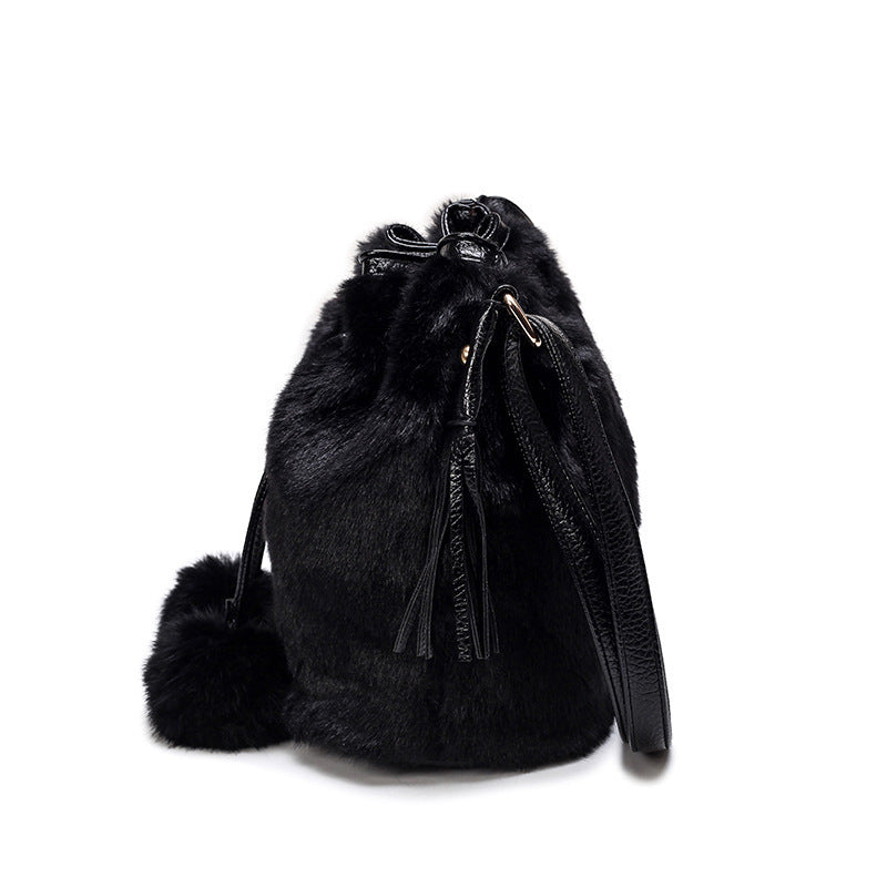Black faux-fur drawstring bucket bag with tassels and hanging key charm