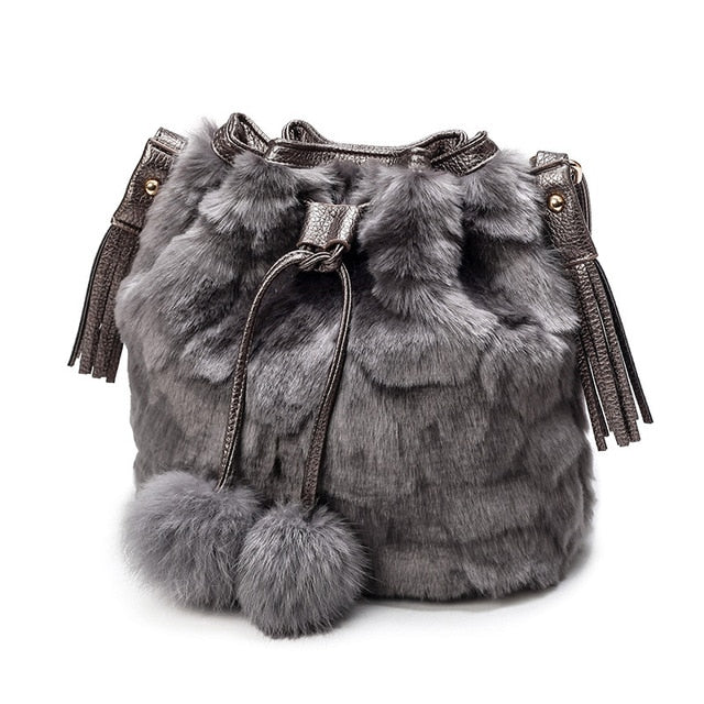 Grey faux-fur drawstring bucket bag with tassels and two pom-pom charms