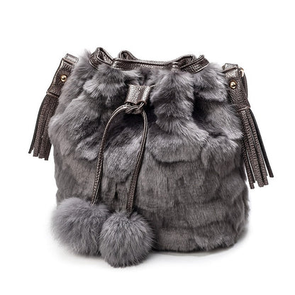 Grey faux-fur drawstring bucket bag with tassels and two pom-pom charms