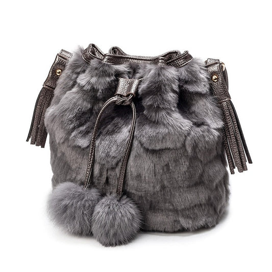 Grey faux-fur drawstring bucket bag with tassels and two pom-pom charms