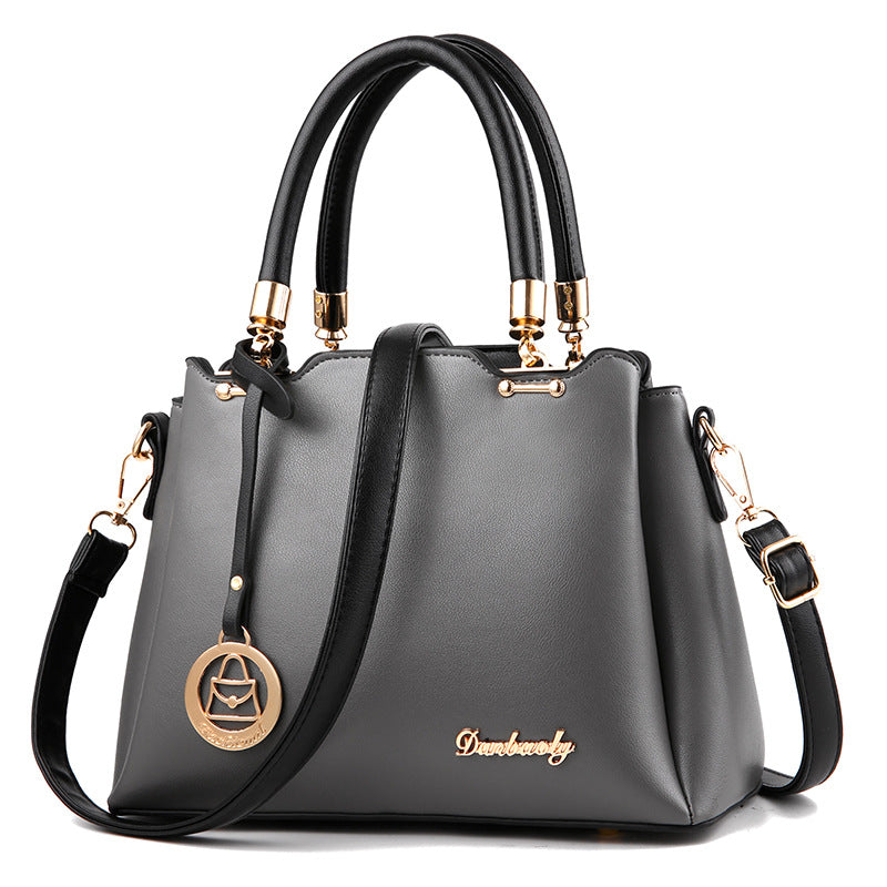 Dark gray women’s handbag with top handles, gold-tone hardware, and crossbody strap