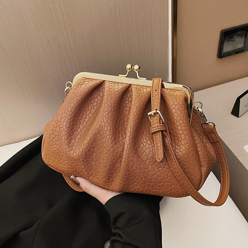 Camel textured clutch-style handbag with kiss-lock frame and wrist strap