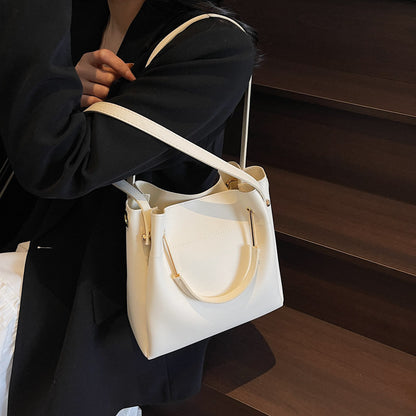 Cream bucket bag with top handles and long crossbody strap, side pocket detail