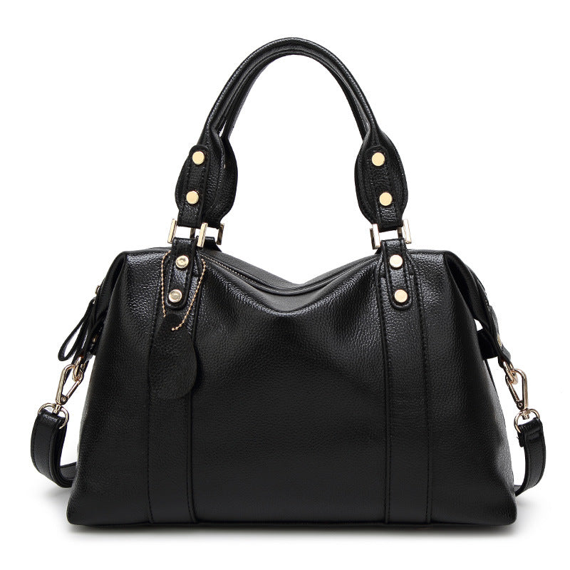 Black shoulder handbag with dual handles, gold-stud strap tabs, and side tassel pulls