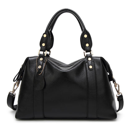 Black shoulder handbag with dual handles, gold-stud strap tabs, and side tassel pulls