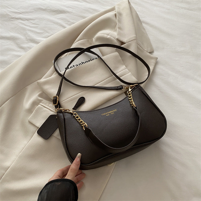 Black pebbled shoulder crossbody bag with gold chain strap and adjustable black shoulder strap