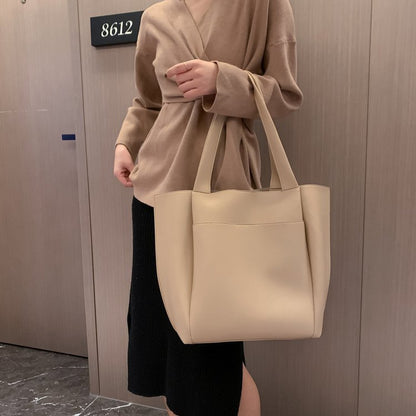 Beige large-capacity tote handbag with two top handles and minimal, smooth front