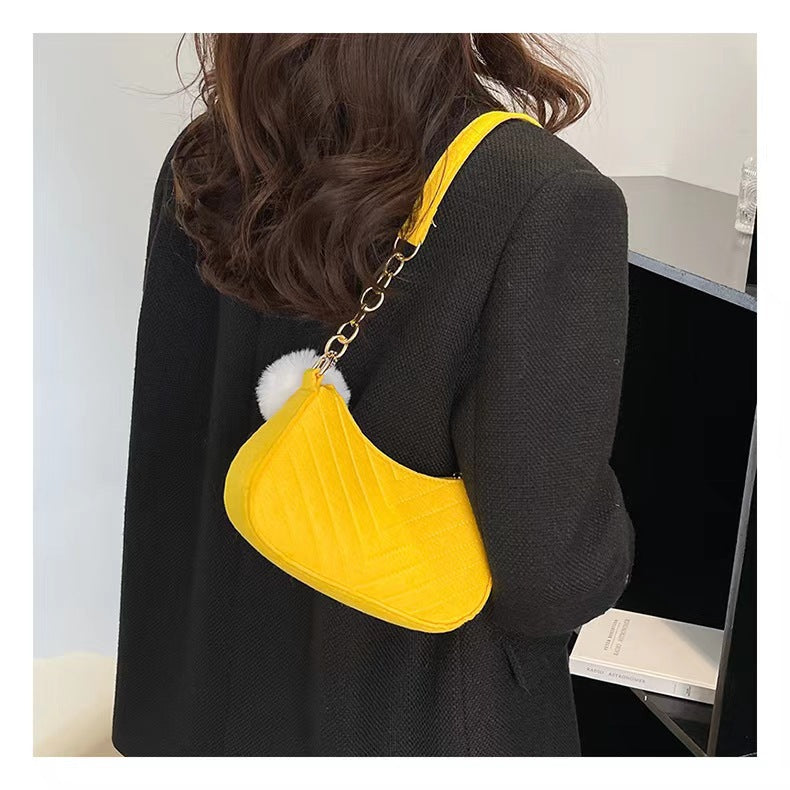 Yellow felt crossbody bag with gold chain strap and white pom-pom charm
