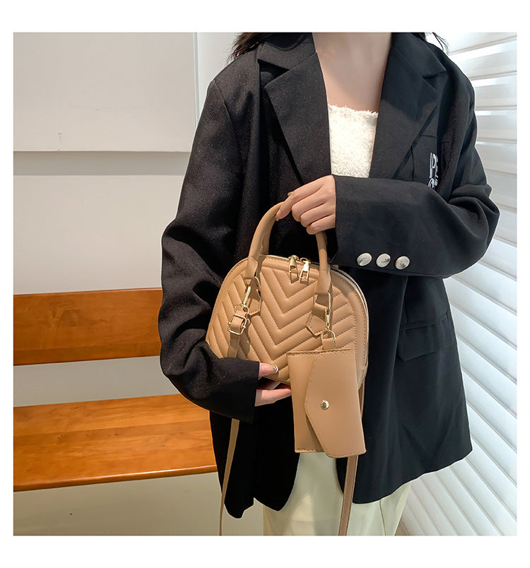Tan quilted women's shoulder messenger bag with top handle, strap, and side charm