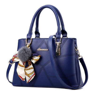 Navy quilted top-handle handbag with adjustable crossbody strap and bow charm