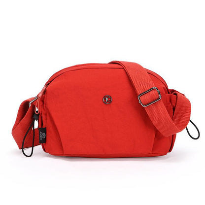 Small red nylon crossbody bag with adjustable strap and zip closure