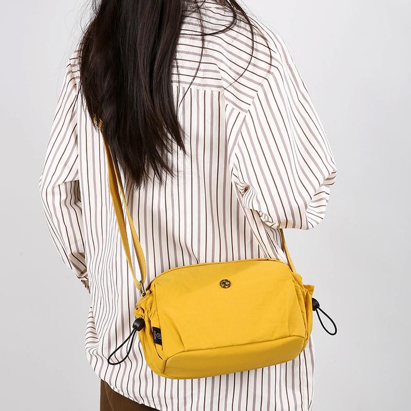 Small yellow nylon crossbody bag with adjustable strap and zip closure