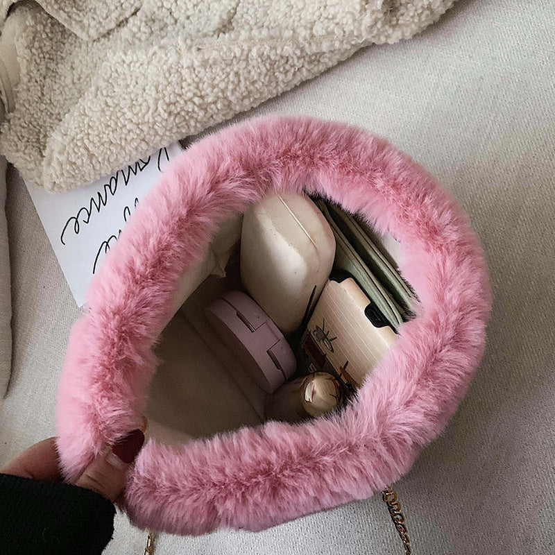 Pink plush mini shoulder bag open at top, showing small items inside