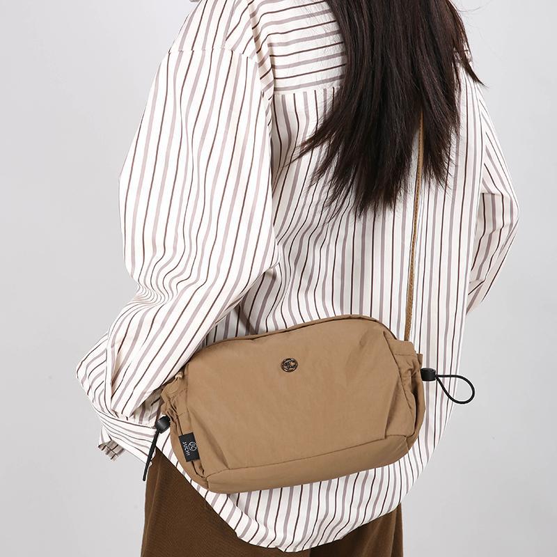 Small tan nylon crossbody bag with adjustable strap and zip closure