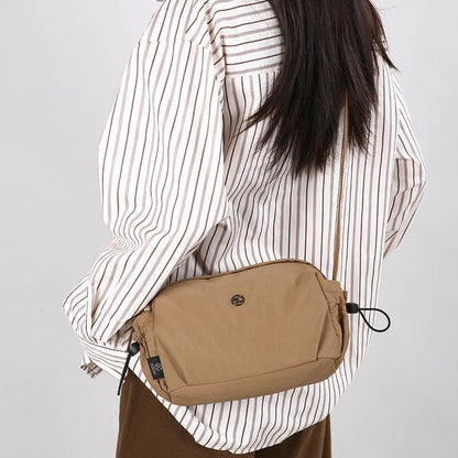 Small tan nylon crossbody bag with adjustable strap and zip closure