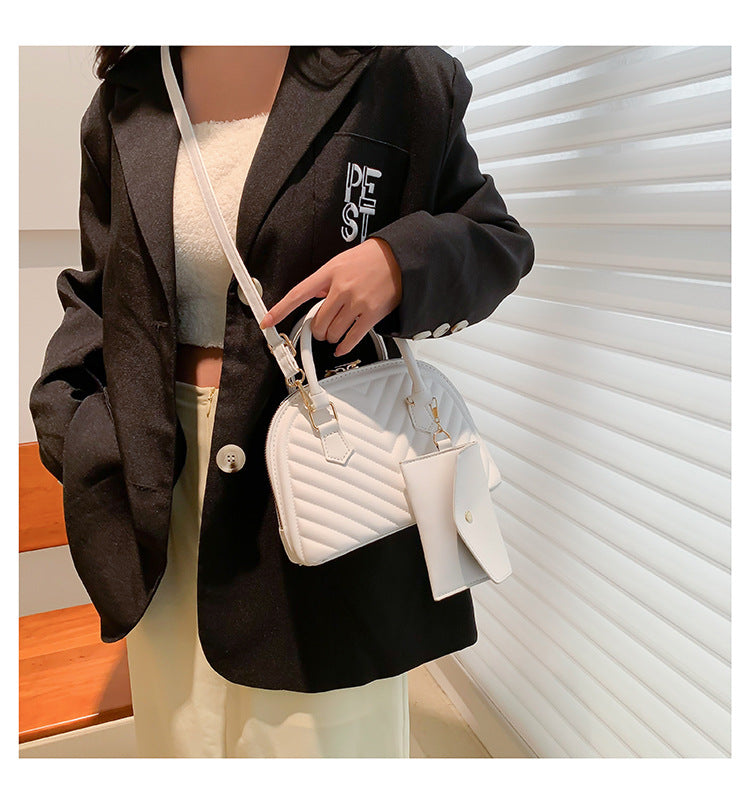 White quilted women's shoulder messenger bag with top handle, strap, and front charm