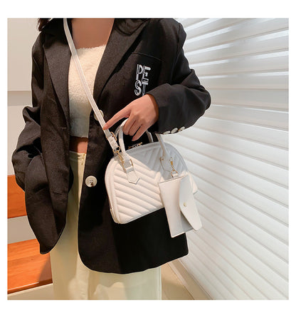 White quilted women's shoulder messenger bag with top handle, strap, and front charm