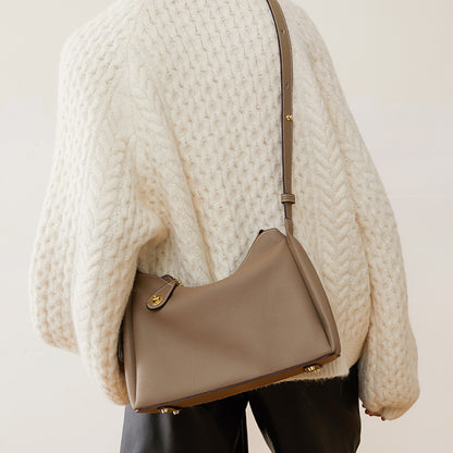 Beige mini crossbody bag worn on shoulder with short strap and gold clasp