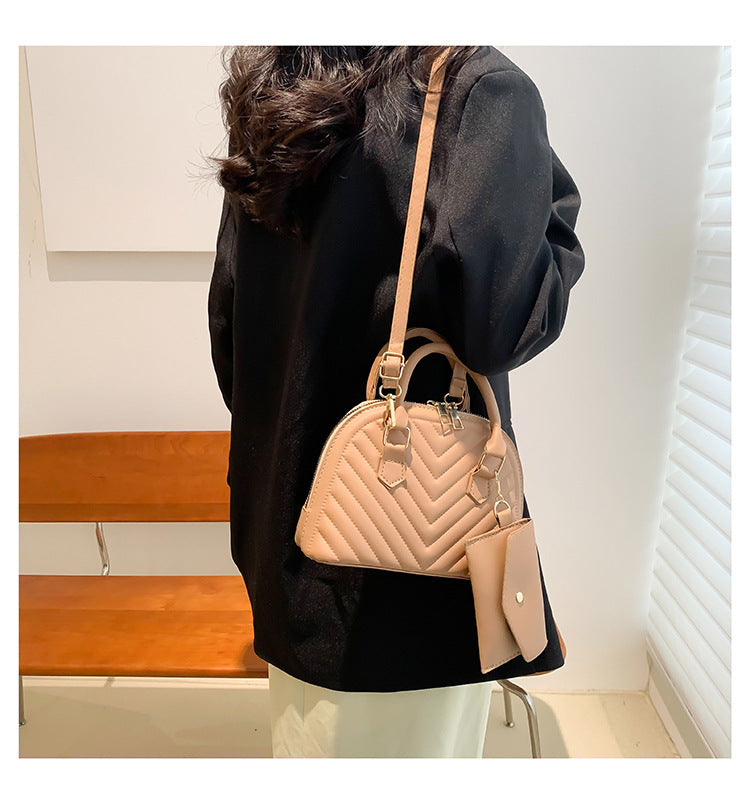 Light tan quilted women's shoulder messenger bag with top handle and crossbody strap