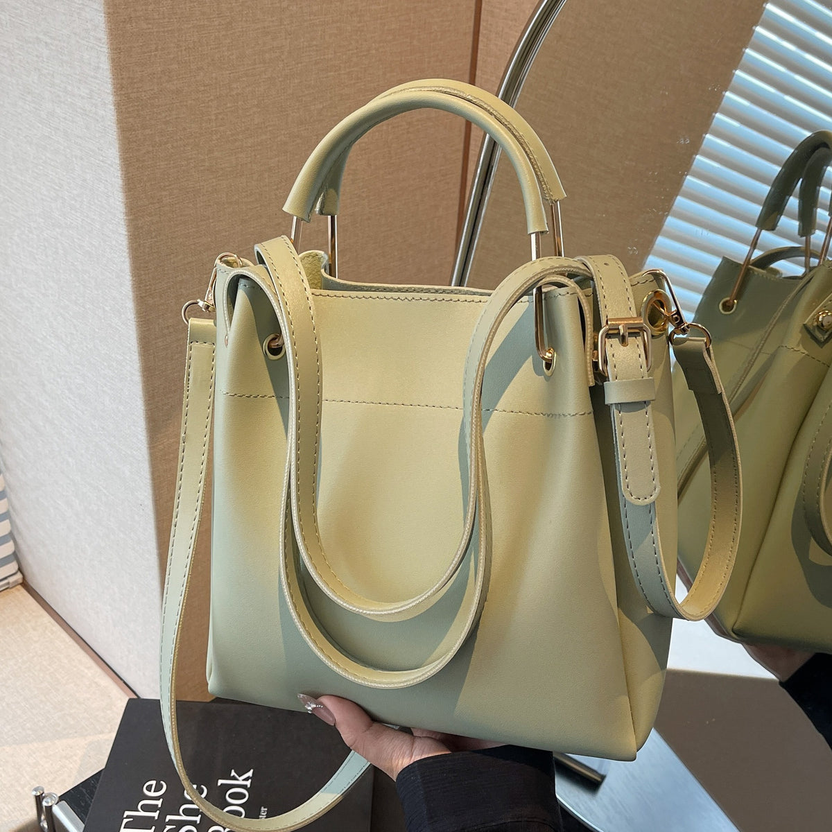 Light green bucket bag with curved top handle and adjustable shoulder strap