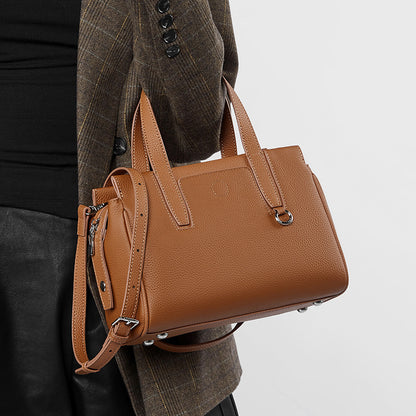 Tan crossbody bag with front zipper pocket, double handles, and adjustable shoulder strap