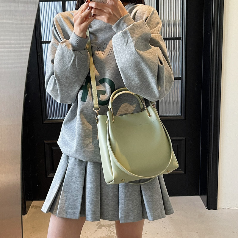 Light green bucket bag with curved handle and adjustable shoulder strap