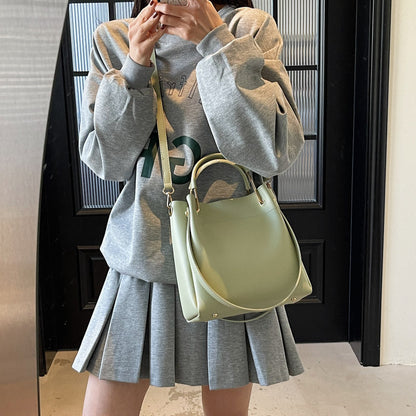 Light green bucket bag with curved handle and adjustable shoulder strap