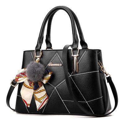 Black quilted top-handle handbag with adjustable crossbody strap and charm