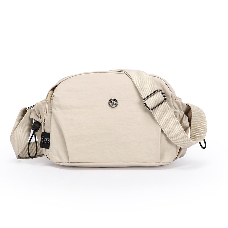 Small cream nylon crossbody bag with adjustable shoulder strap and zip closure