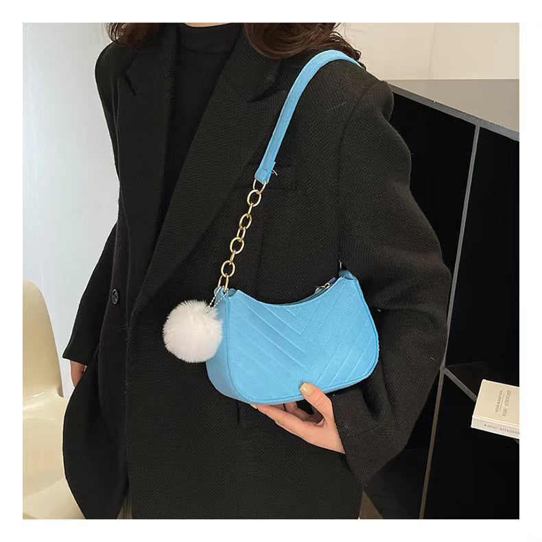 Light blue felt crossbody bag with gold chain and white pom-pom detail