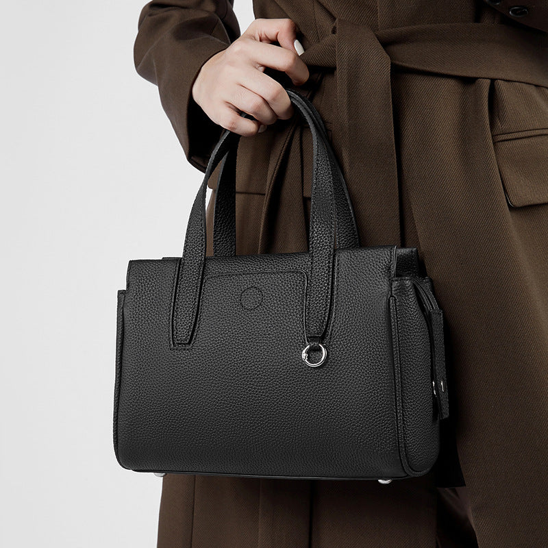 Black structured crossbody bag with top handles, front pocket, and zipper compartment