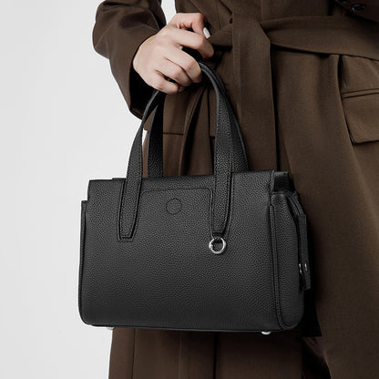 Black structured crossbody bag with top handles, front pocket, and zipper compartment