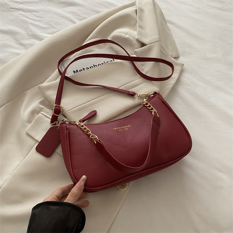 Red pebbled shoulder crossbody bag with gold chain strap, curved flap, and side tassel