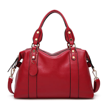 Red leather shoulder bag with dual handles, studded strap tabs, and side tassel pulls